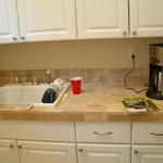 Laundry Room cabinet installation with travertine tile counters and backsplash